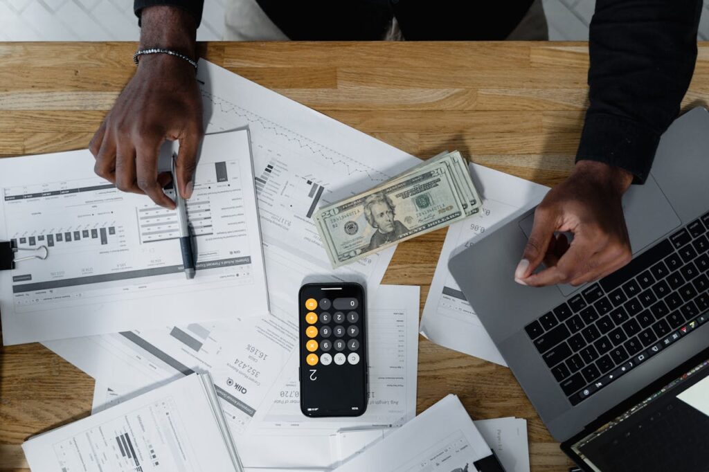 Small business accounting Small business accounting setup featuring a laptop, documents, and smartphone calculator.